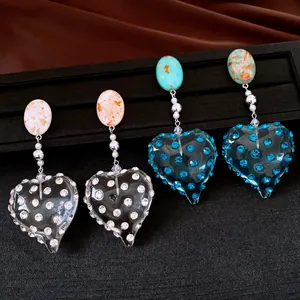 Dettaglio di orecchini vintage a cuore in resina con strass luccicanti e perni in argento