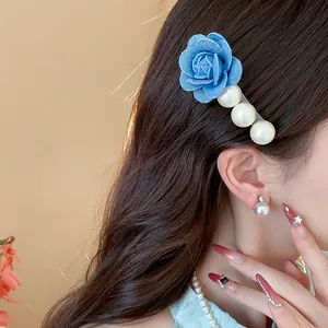 Detailed shot of a French style blue fabric flower hair clip with elegant white pearls.