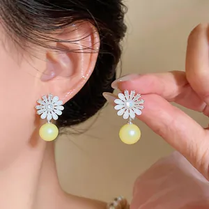 Detailed view of floral zircon stud earrings with cream pearl drop on ear