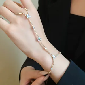 Detailed view of elegant gold hand chain with sparkling rhinestone flower charms on hand