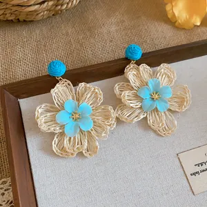 Detailed macro view of bohemian raffia flower earrings with blue floral center