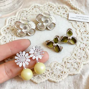 Detail of French style floral stud earrings with zircon accents and yellow pearls