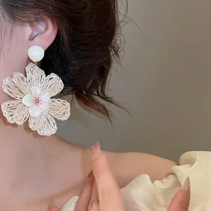 Detailed macro view of Bohemian style woven raffia flower earring in fresh summer white