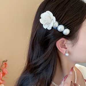 Close-up of elegant white fabric flower and pearl hair clip worn on dark hair