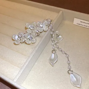 Exquisite hair clip featuring rhinestone pearl flowers and long tassels on a jewelry tray.