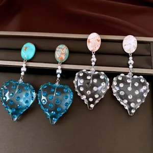 Vista dettagliata di orecchini vintage a cuore in resina con strass blu e bianchi scintillanti