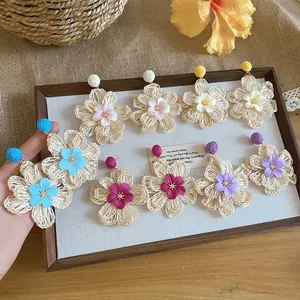 Detailed view of colorful hand-woven raffia flower earrings in bohemian summer style