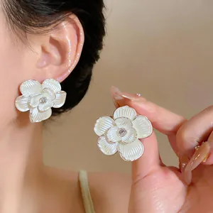 Detailed view of elegant white enamel flower stud earrings with a central zircon stone