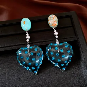 Dettaglio ravvicinato di orecchini vintage a cuore in resina blu con strass scintillanti