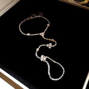 Detailed view of a dainty gold-tone hand chain bracelet set with sparkling rhinestones