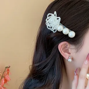 Close-up detail of elegant pearl flower hair clip and matching pearl stud earring.