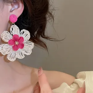 Close-up detail of bohemian raffia flower earrings in pink and cream
