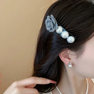 Detail view of a French style fabric flower and pearl hair clip worn by a model.