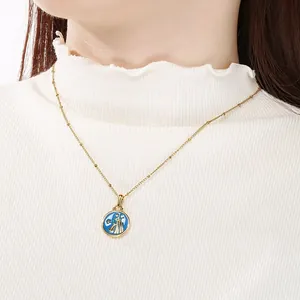 Primer plano de collar de acero dorado con colgante de signo Géminis en esmalte azul
