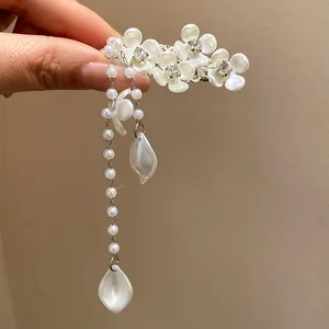 Close-up of elegant pearl flower hair clip with rhinestone centers and tassels.