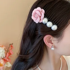 Close-up of a French style hair clip with a pink fabric rose and three pearls on dark hair