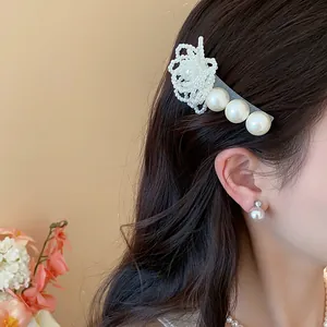 Detailed close-up showing a French fabric flower hair pin with pearls on dark hair