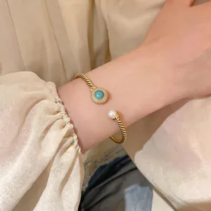 Detailed close-up of 18K gold plated twisted cable bangle with turquoise stone and pearl