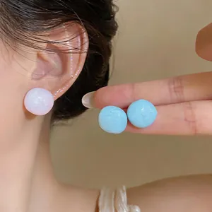 Dettaglio di dolci orecchini a lobo in smalto blu pastello e rosa per donne e ragazze