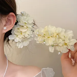 Détail d'une élégante pince à cheveux en fleur de tissu blanc avec perles sur le modèle