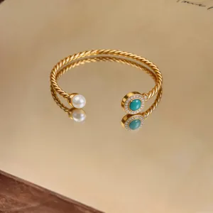 Detail view of 18K gold plated twisted cable cuff bracelet with pearl and turquoise.