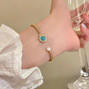 Close-up detail of 18K gold plated twisted bangle with turquoise and pearl on wrist