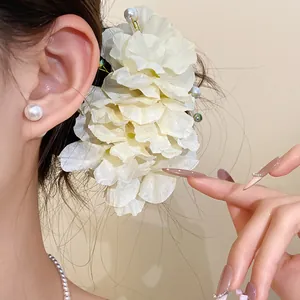 Détail rapproché d'une élégante pince à cheveux fleur en tissu blanc avec perles délicates