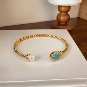 Detail view of an 18K gold plated twisted cuff bracelet with pearl and turquoise