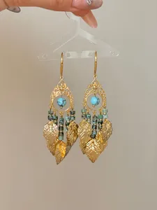 Detailed macro shot of vintage bohemian gold leaf tassel earrings with turquoise beads