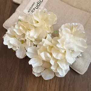 Barrettes à fleurs en tissu crème élégantes avec perles sur un sac en lin rustique.