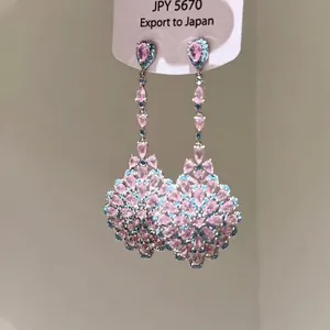 Gros plan d'élégantes boucles d'oreilles pendantes en pierres roses et bleues.