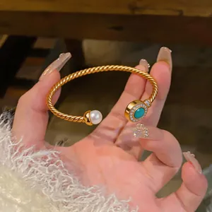 Close-up of 18K gold plated twisted cuff bracelet with pearl and turquoise stone
