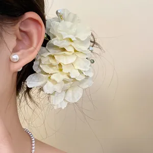 Vue détaillée d'une élégante pince à cheveux en tissu crème ornée de perles sur modèle