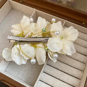 Gros plan d'une barrette à fleurs en tissu avec perles dans un coffret à bijoux élégant