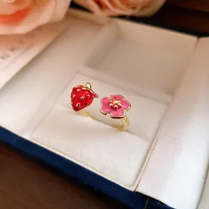 Close-up detail of a sweet strawberry and pink flower adjustable open ring in gold finish.