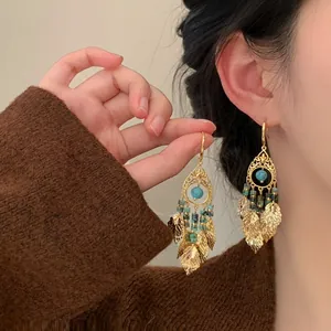 Close-up of ethnic style gold filigree earrings with blue beads and leaf tassels