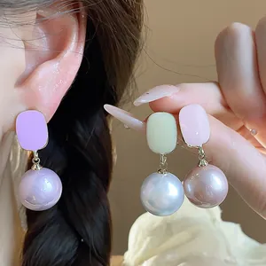Close-up of French style enamel square stud earrings with pearl pendants in pastel colors.