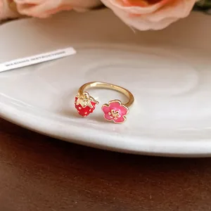 Detailed macro view of a sweet enamel strawberry and pink flower open ring in gold finish