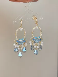 Detail of elegant ethnic style gold-tone earrings with blue glass teardrops and pearls.