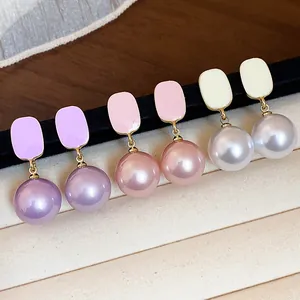 Detailed view of three pairs of elegant square pearl drop earrings in purple, pink, and cream