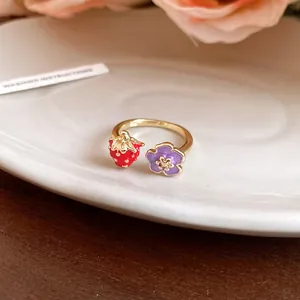 Close-up of gold enamel open ring with strawberry and purple flower charms