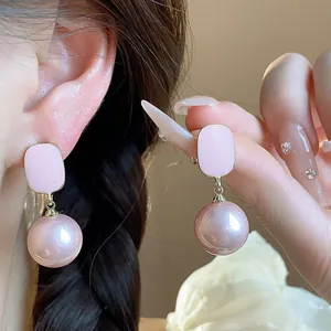 Detailed view of elegant French style pink enamel square stud and pearl drop earrings