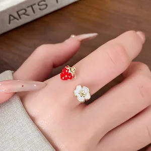 Close-up of strawberry and flower open ring on finger showing fine oil drip detail