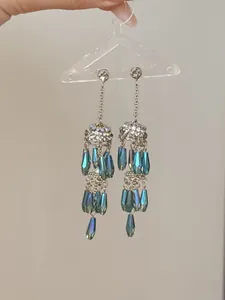 Detailed view of long tassel earrings with blue teardrop glass beads and rhinestones