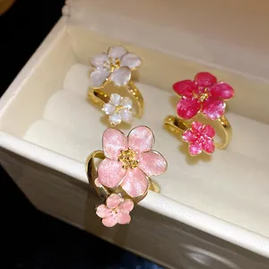 Detailed macro shot of three vintage-style enamel flower rings in white and pink shades.