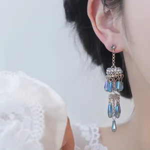 Elegant silver needle tassel earrings featuring blue geometric faceted glass beads.
