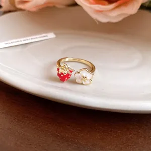 Detailed close-up of a golden strawberry and flower open ring on a white porcelain plate