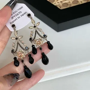 Close-up of vintage silver tassel earrings featuring black faceted beads and floral detail