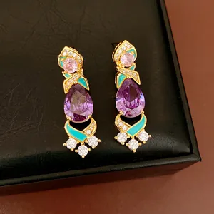 Detail view of ornate court style earrings with purple and pink zirconia and teal enamel.