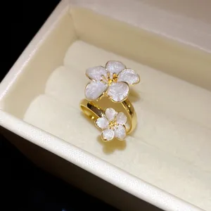 Macro view of a gold-toned flower ring with white pearly petals in a luxury box